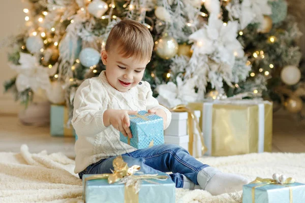 Okouzlující malé dítě chlapec sedí vánoční stromeček s gif — Stock fotografie