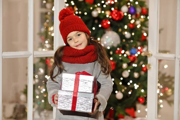 Belle petite fille souriant et tenant un cadeau à Noël st — Photo