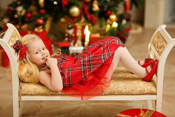 Chica rubia bebé en un vestido rojo al lado del árbol de Navidad está en — Foto de Stock