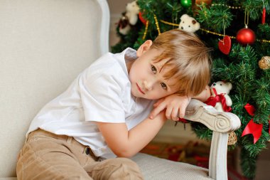 Noel'de bir sandalyede ve üzgün oturan çocuk