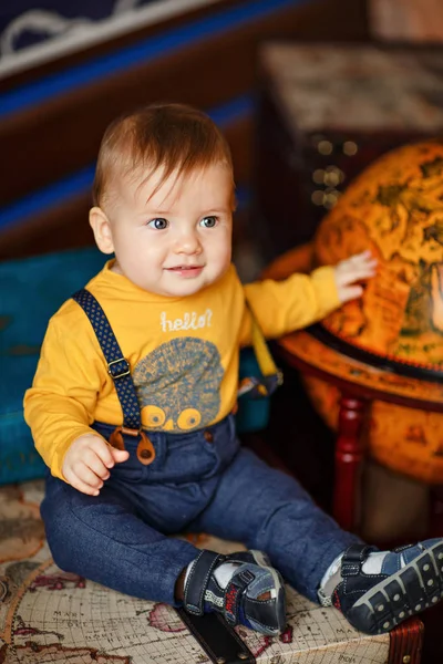 The boy with chubby cheeks smiling next to a globe — Stock Photo, Image