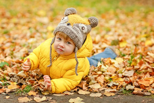 Mały chłopczyk w żółtą kurtkę uśmiecha się jesienią — Zdjęcie stockowe