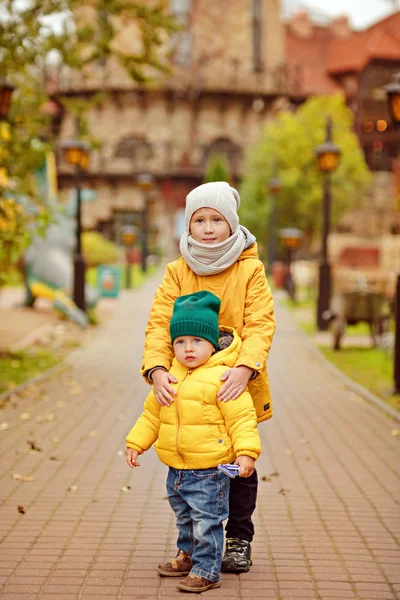 Twee broers knuffel in het najaar van gele jassen — Stockfoto