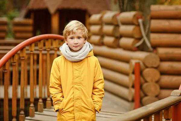 Kleine jongen tiener in een gele jas in het najaar op een backgr — Stockfoto