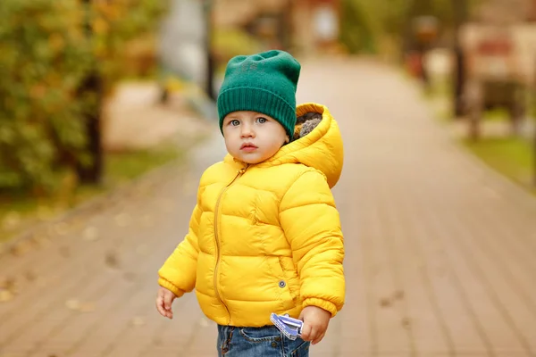 Baby jongetje in een gele jas in de herfst — Stockfoto