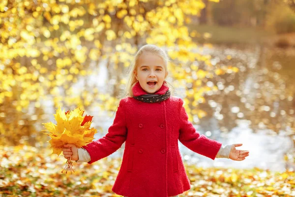 Little girl in coat in autumn in the park laughing happy — Stock Photo, Image