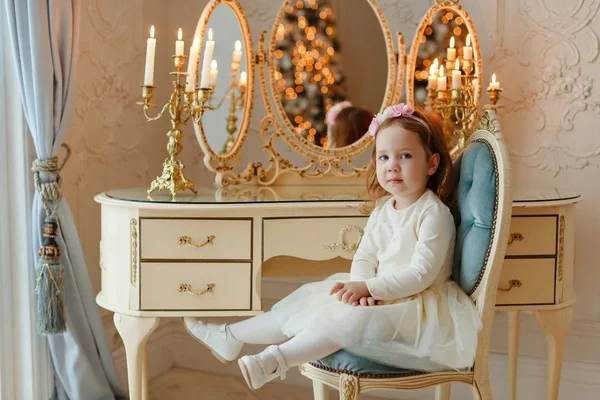 Menina pequena menina sentada em uma cadeira na mesa de vestir — Fotografia de Stock