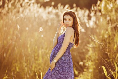 Güzel ihale hamile kadın gülümsüyor ve güneşli bir yaz sahiptir