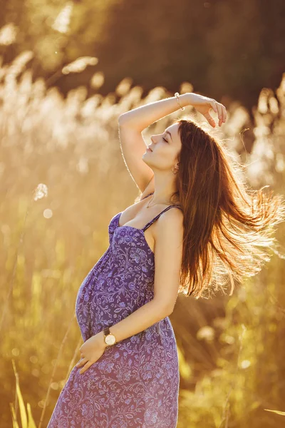 Beautiful tender pregnant woman smiles and enjoys a sunny summer — Stock Photo, Image