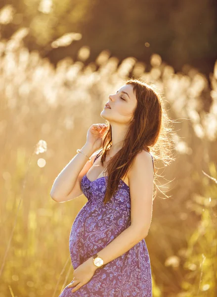 Beautiful tender pregnant woman smiles and enjoys a sunny summer — Stock Photo, Image