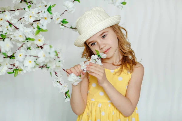Encantadora niña rubia con sombrero y vestido amarillo en una luz — Foto de Stock