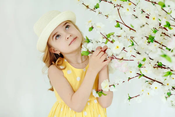 Encantadora niña rubia con sombrero y vestido amarillo en una luz —  Fotos de Stock