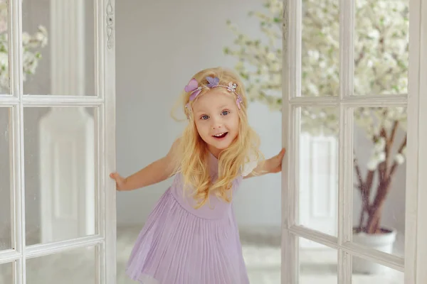 Encantadora niña rubia sonríe contra puertas blancas en la luz s —  Fotos de Stock