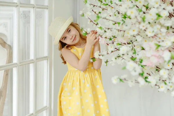 Чарівна маленька дівчинка блондинка в капелюсі і жовта сукня в світлі — стокове фото