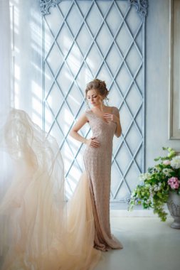 Güzel seksi kız sarışın bej elbise standları ve yavaşça sm