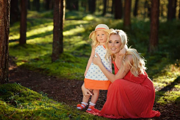 Маленька блондинка і її мама посміхаються в лісі в сонячному су — стокове фото