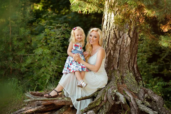 Blond meisje en haar moeder lacht zittend op een boom in de — Stockfoto