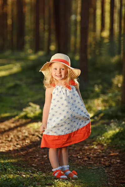 O fetiță blondă într-o rochie strălucitoare și pălărie merge într-un pin — Fotografie, imagine de stoc