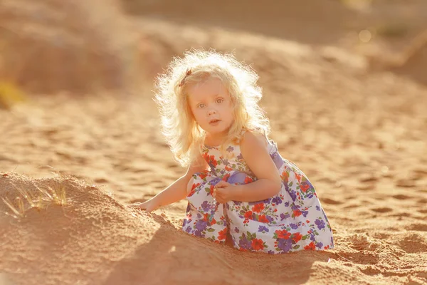 金发碧眼的小女孩坐在海岸的海湾和玩 s — 图库照片