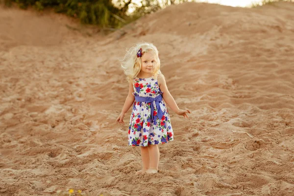 Ein kleines blondes Mädchen läuft entlang der Küste der Bucht auf dem Sand — Stockfoto