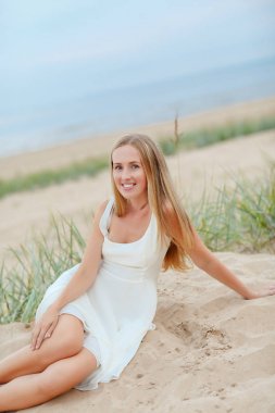 Yaz aylarında deniz kıyısında tozlar çekici sarışın kız oturuyor