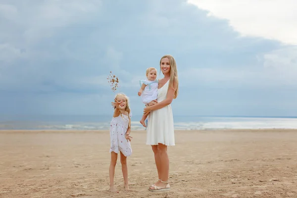 Mutter die Blondine und zwei Töchter spielen und lachen am Meer — Stockfoto