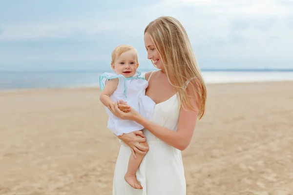 Mamá y pequeña niña encantadora bebé en la playa en verano — Foto de Stock