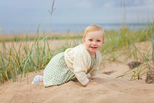 Charmante kleine meisje meisje zit op het zand door de zee-sho — Stockfoto