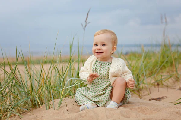 Charmante kleine meisje meisje zit op het zand door de zee-sho — Stockfoto