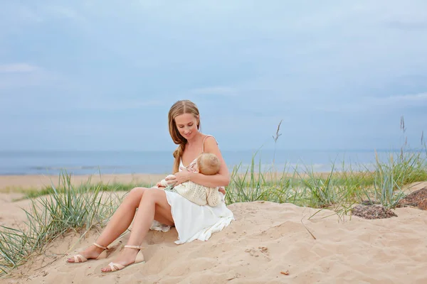 S sahilde kum üzerinde oturan Anne ve emzirme, Bebek — Stok fotoğraf