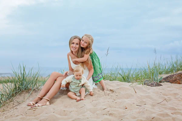 Mamá la rubia y dos hijas abrazan y se ríen en el seasho — Foto de Stock