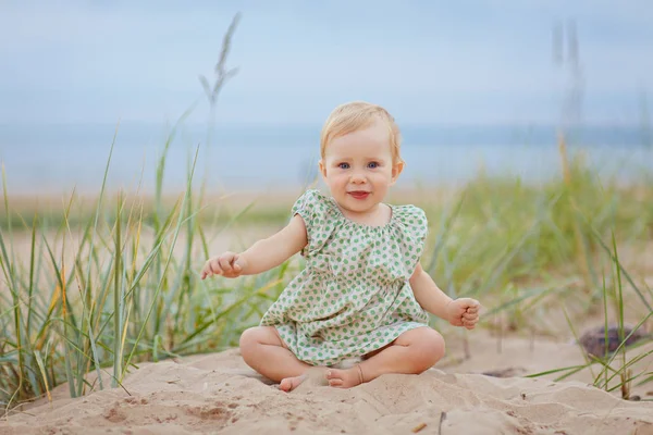 Pequeña niña encantadora se sienta en la arena junto al mar sho —  Fotos de Stock
