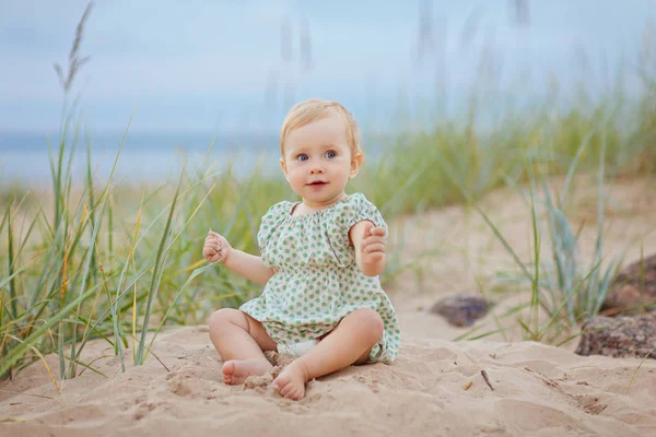 Pequeña niña encantadora se sienta en la arena junto al mar sho —  Fotos de Stock