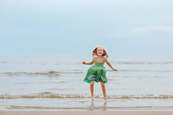 Petite fille blonde éjacule et rit au bord de la mer en été — Photo