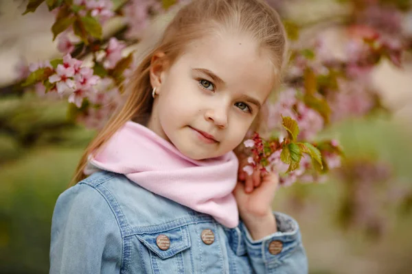 Aranyos szőke lány mosolyog hátterében a rózsa sakura bu — Stock Fotó