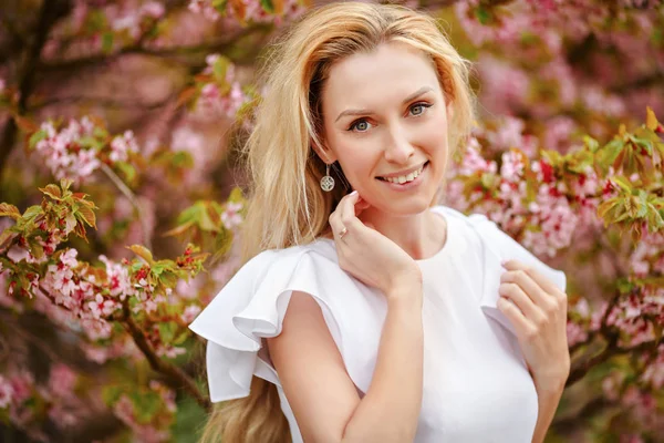 Blond flicka med långa hår ler mot bakgrund av rosa — Stockfoto