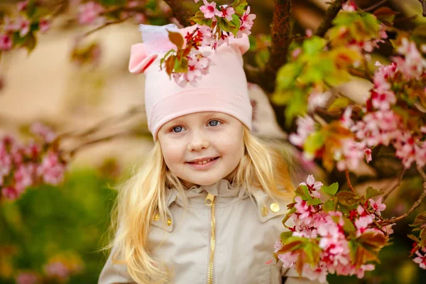 Een leuke charmante blond meisje met weelderige haren op een roze sakura spri — Stockfoto