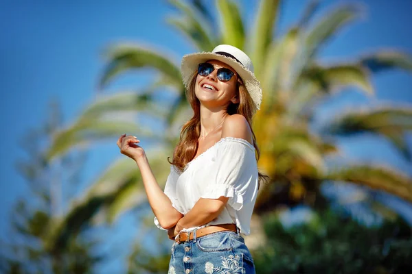 Tanned beautiful and sexy girl in a white hat and glasses smiles — Stock Photo, Image