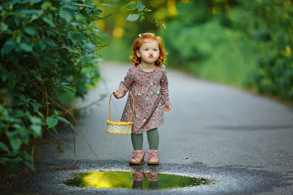 Mooie roodharige meisje babymeisje staat in de buurt van een plas — Stockfoto