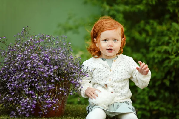 Little beautiful red-haired girl baby girl smiling and holding a — Stock Photo, Image