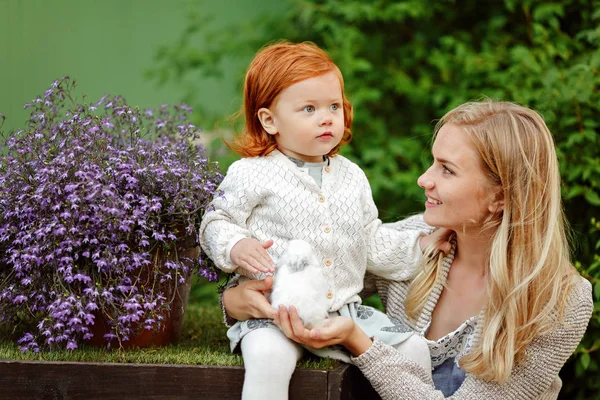 Мама и рыжеволосая дочь держат кролика летом в й — стоковое фото