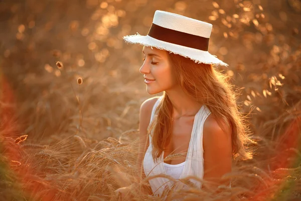 Retrato de uma menina bonita em um vestido branco e chapéu no fie — Fotografia de Stock