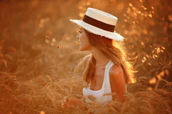 Porträtt av en vacker flicka i en vit klänning och hatt i den fie — Stockfoto
