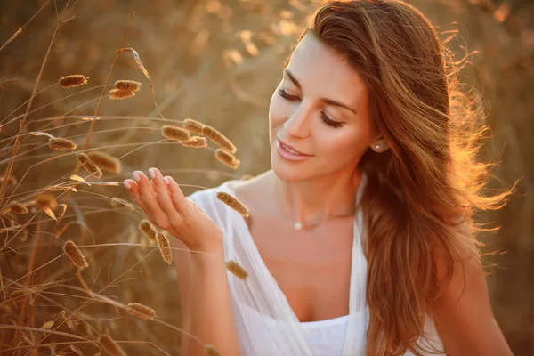 Porträt eines schönen Mädchens in einem weißen Kleid auf einem Feld bei Sonnen — Stockfoto