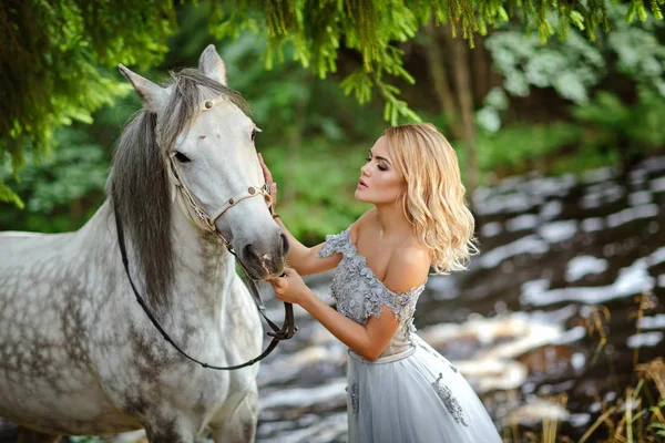 美丽苗条的金发女孩，抱着一匹灰色的马，outd 穿着 — 图库照片