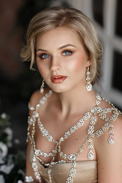 Портрет блондинки з блакитними очима в золотій сукні з ювелірними виробами — стокове фото