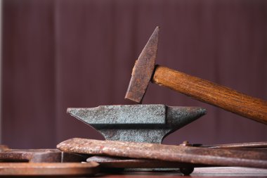 Eski paslı engebeli örs, çekiç ve diğer demirci araçları.