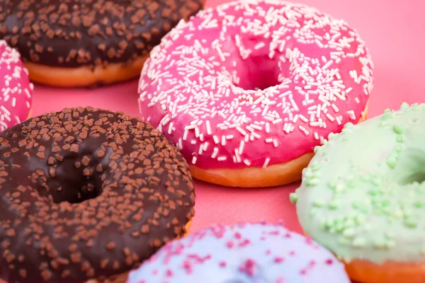 Сладкие красочные вкусные пончики на розовом фоне . — стоковое фото