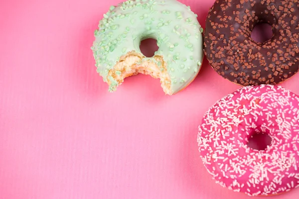 Сладкие красочные вкусные пончики на розовом фоне . — стоковое фото