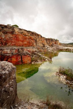Brezilya 'daki Minas Gerais eyaletlerinde kırmızı kaya katmanları ve yeşil su katmanları olan eski bir taş ocağı.